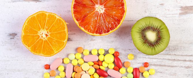 Fresh fruits and colorful medical pills, choice between healthy nutrition and medical supplements