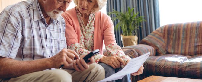 Front view of active Senior Caucasian couple calculating bill while sitting at retirement home